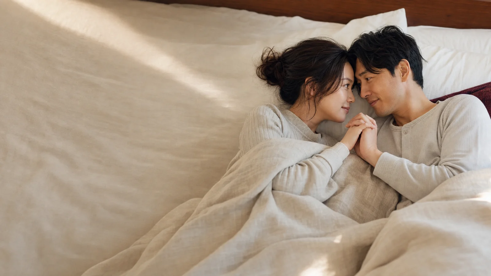 スローセックス無料体験をイメージした、ゆっくり見つめ合い手を重ねる成人カップル